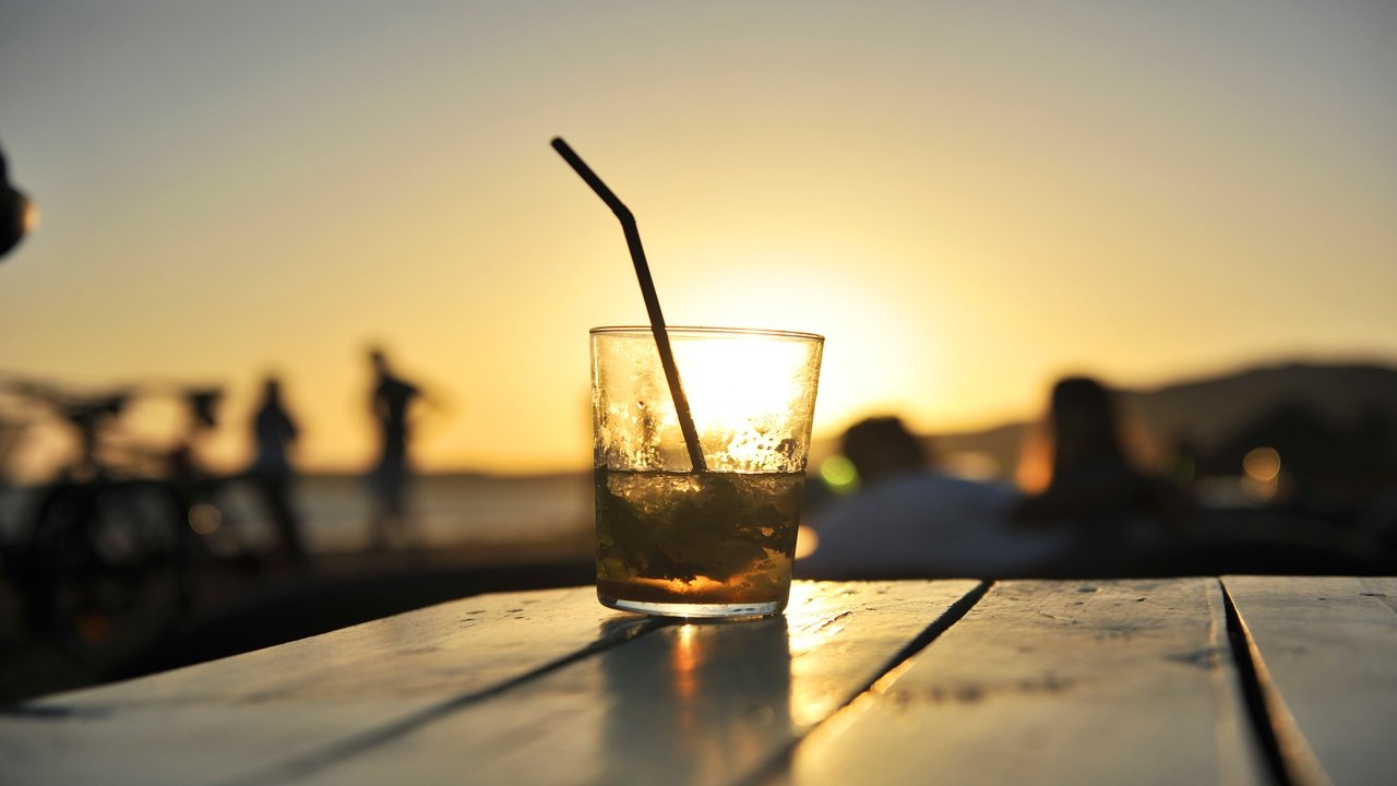 Verre sur la table du bar de plage au coucher du soleil