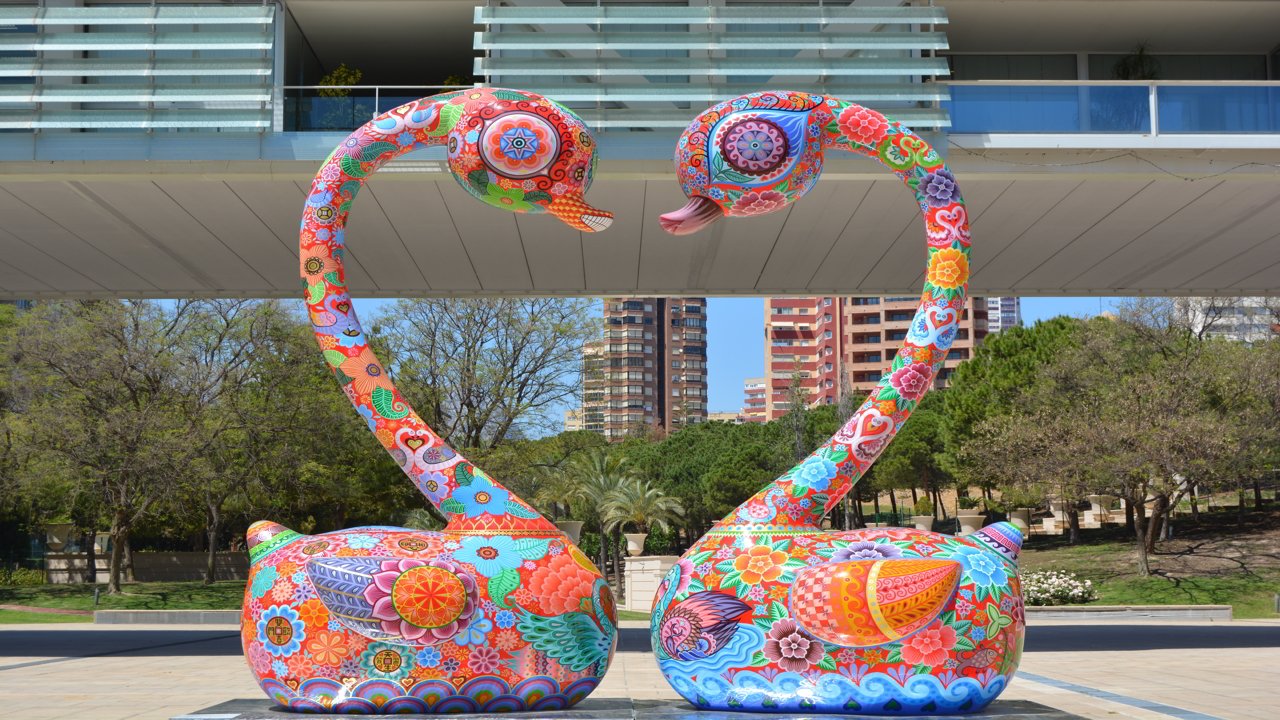 Figures of two, coloured swans in a park
